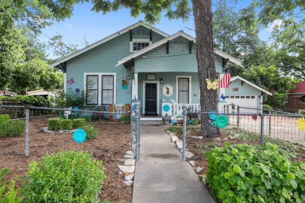 a blue bungalow and a front yard in fredericksburg tx