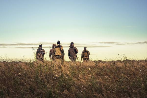 five hunters stand in a field in fredericksburg texas under a clear sky