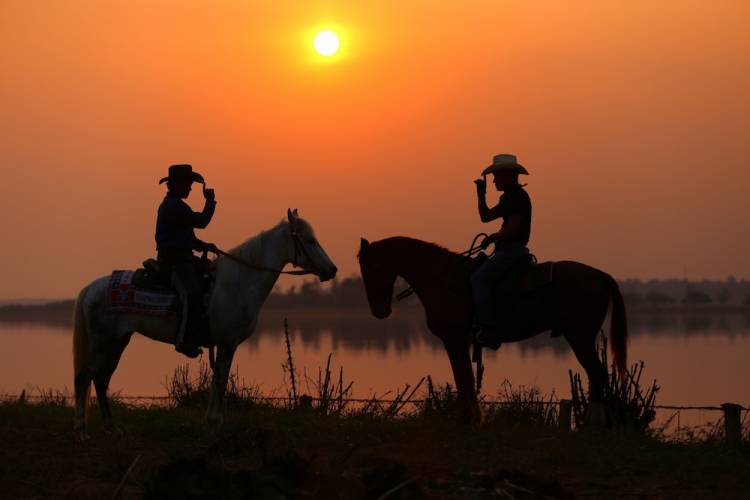 Two cowboys salute at sunset