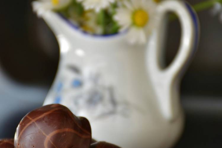 A bouquet of flowers in a pitcher with chocolates on a plate A bouquet of flowers in a pitcher with chocolates on a plate
