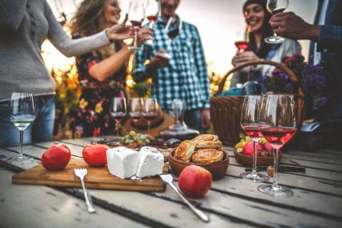 Winery five friends swirl glasses of red wine in front of a table with food pairings