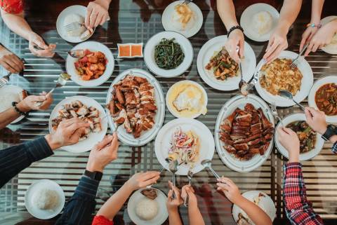 Family Food eight pairs of hands reach with utensils toward plates of food on a table