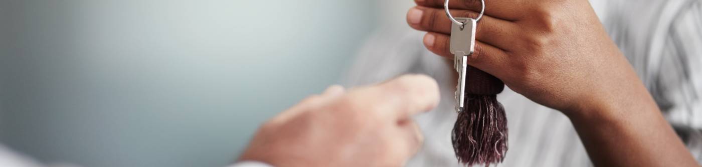 a woman out of focus gives a key to a hand in focus
