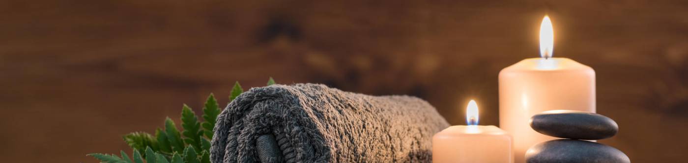 A towel, rocks, and candles prepared for a massage therapist to use