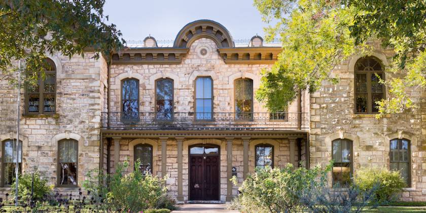 the pioneer memorial library in fredericksburg, texas. the building has two floors built with limestone in a romanesque revival style.